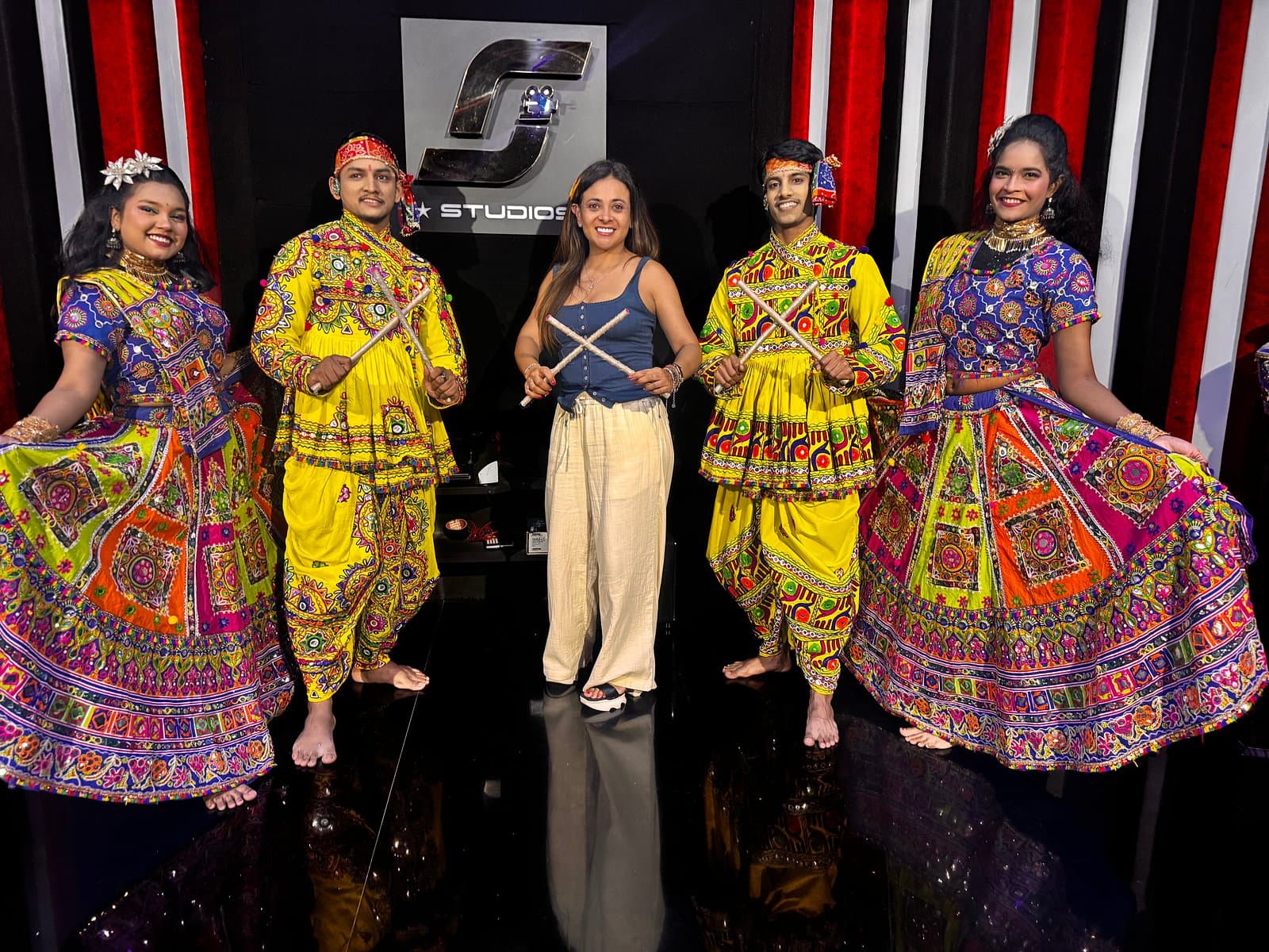 A guest with dancers in traditional costume on the studio stage