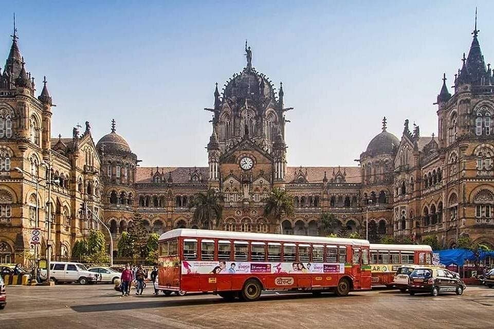 A red BEST bus passing Chhatrapati Shivaji Maharaj Terminus
