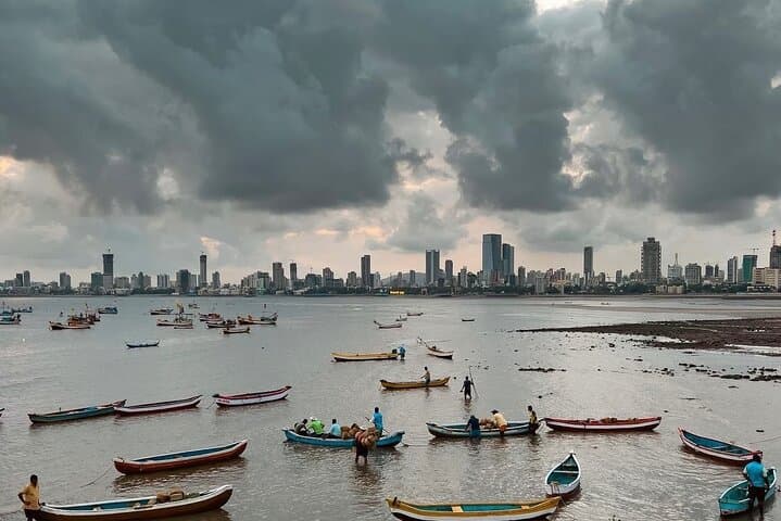 Fishing boats in the bay with the Mumbai skyline under monsoon clouds