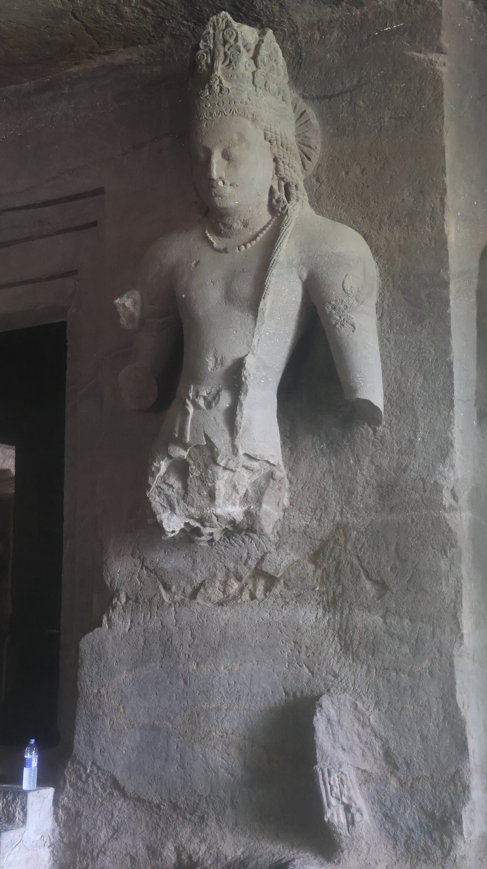 A carved doorkeeper figure beside a cave entrance