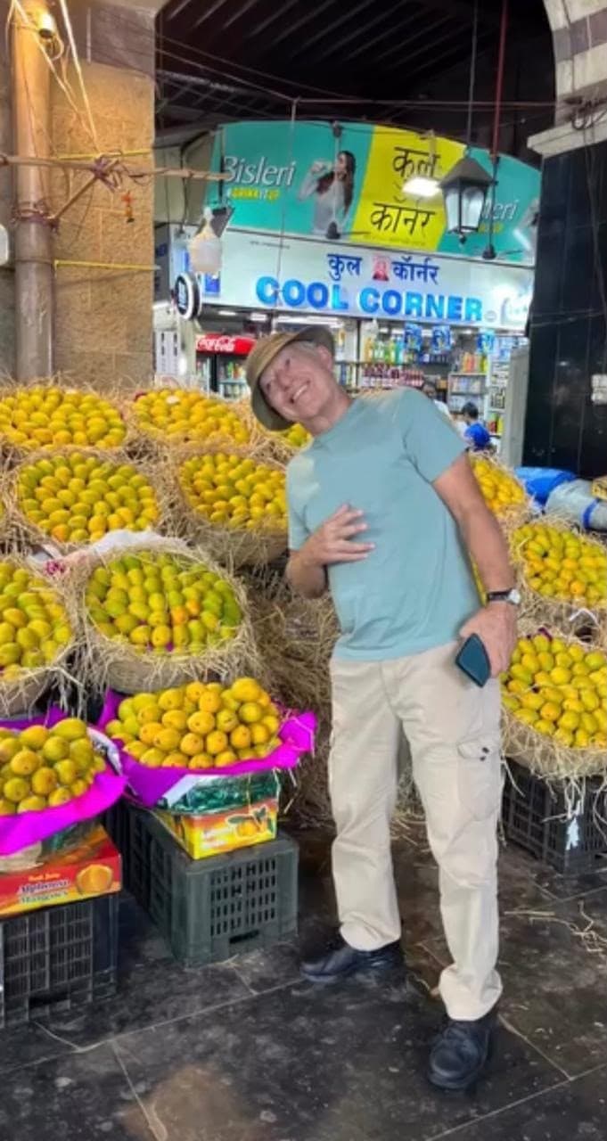 A guest beside crates of mangoes at a market