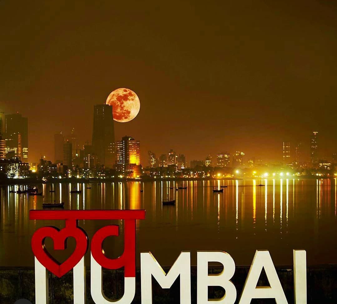 The Love Mumbai sign lit at night under a full moon