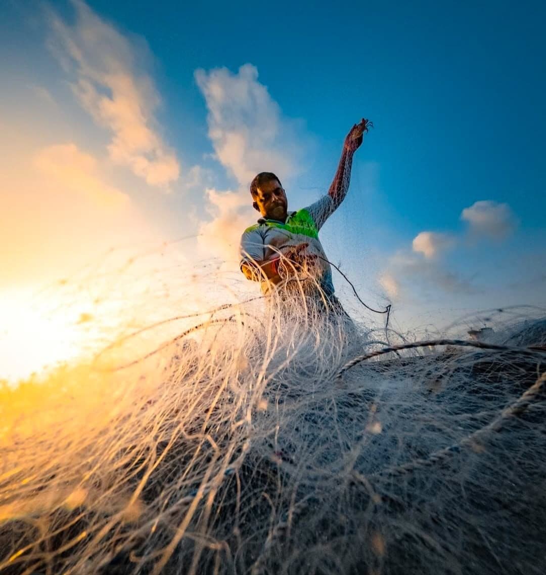 A fisherman casting his net at sunrise
