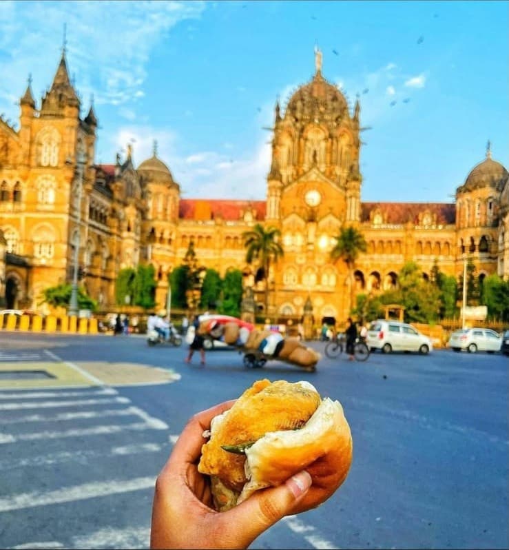 A vada pav held up in front of CST