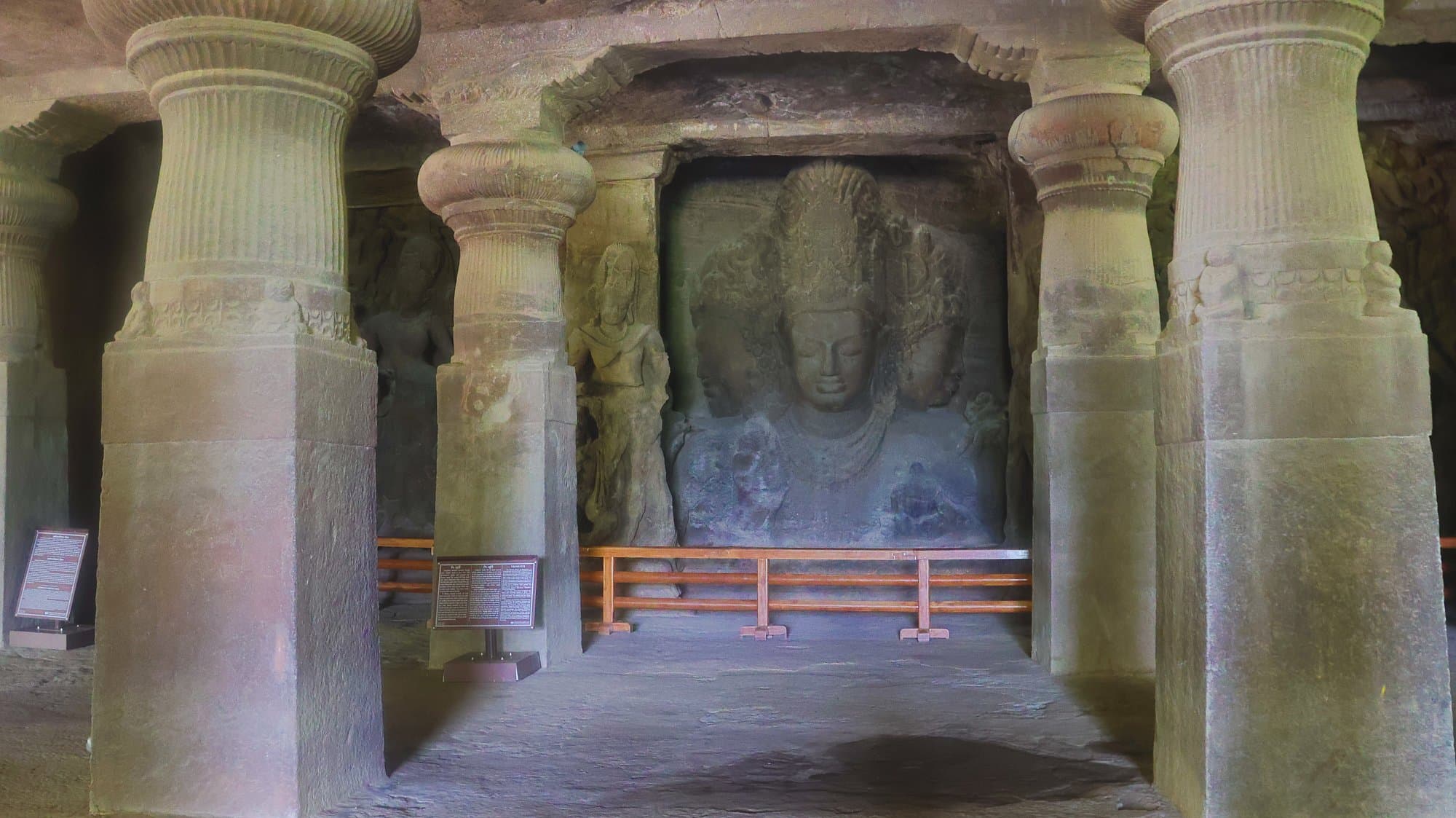 The Trimurti seen between the pillars of the main cave at Elephanta